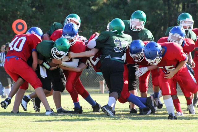 アメリカンフットボールの試合で選手たちがボールを奪い合う写真